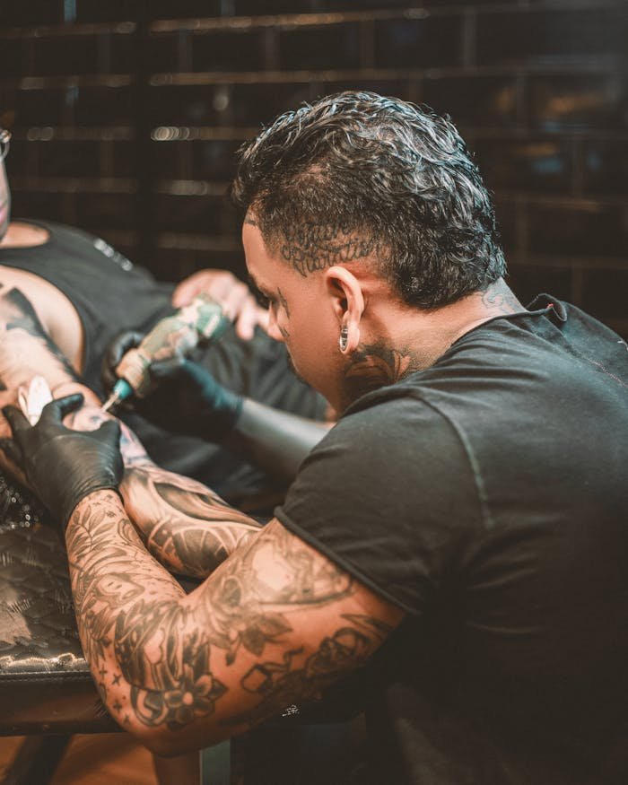 bachelor-party-03 Tattoo artist skillfully tattooing a clients arm with precision and care.