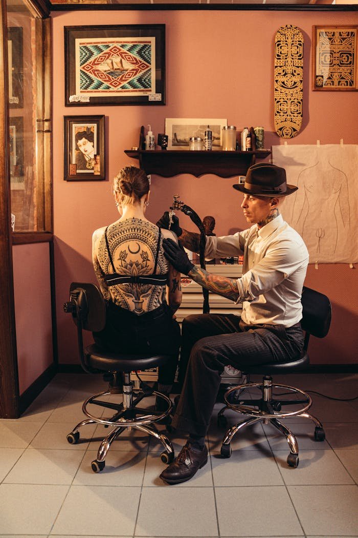 private-party-01 An artist creating a detailed back tattoo in a stylish tattoo studio.