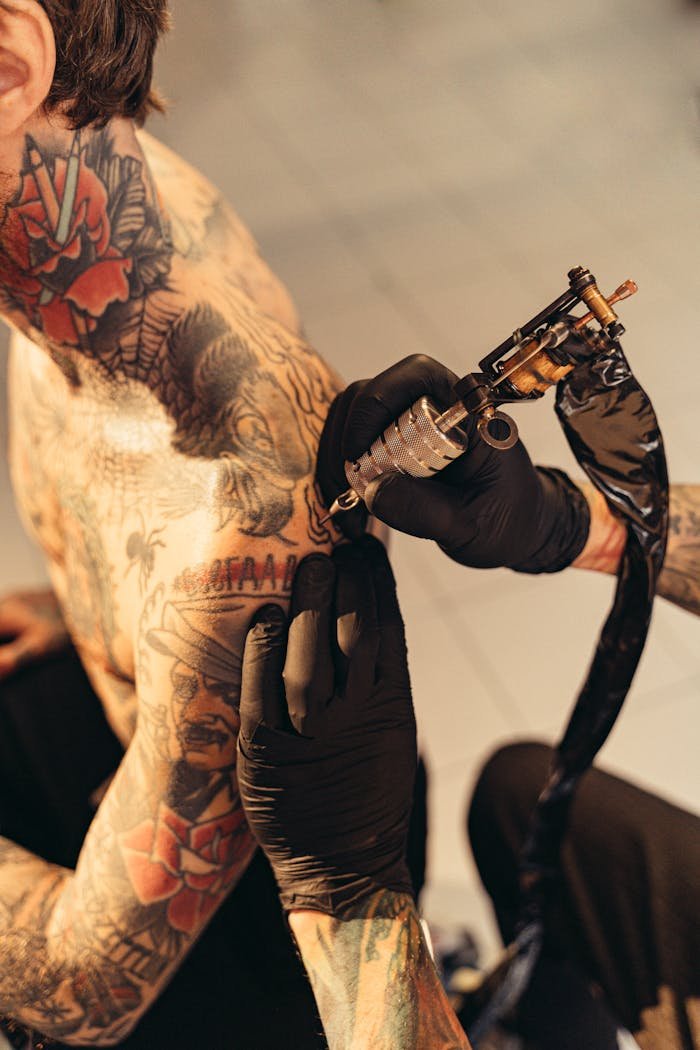 service-05 Tattoo artist skillfully etching detailed design on clients shoulder in studio.