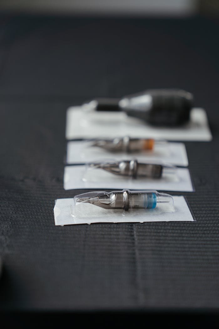 service-01 Close-up of tattoo needles and equipment arranged on a studio table, showcasing tools essential for tattooing.