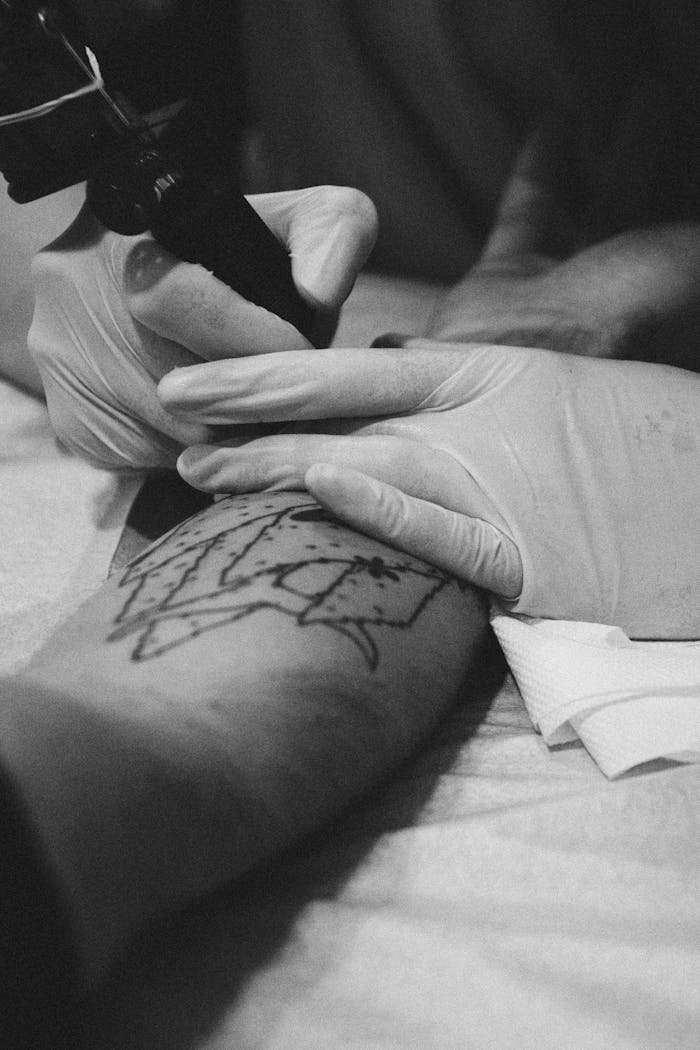 birthday-party-04 Close-up black and white photo of a tattoo artist working on an arm in a studio.