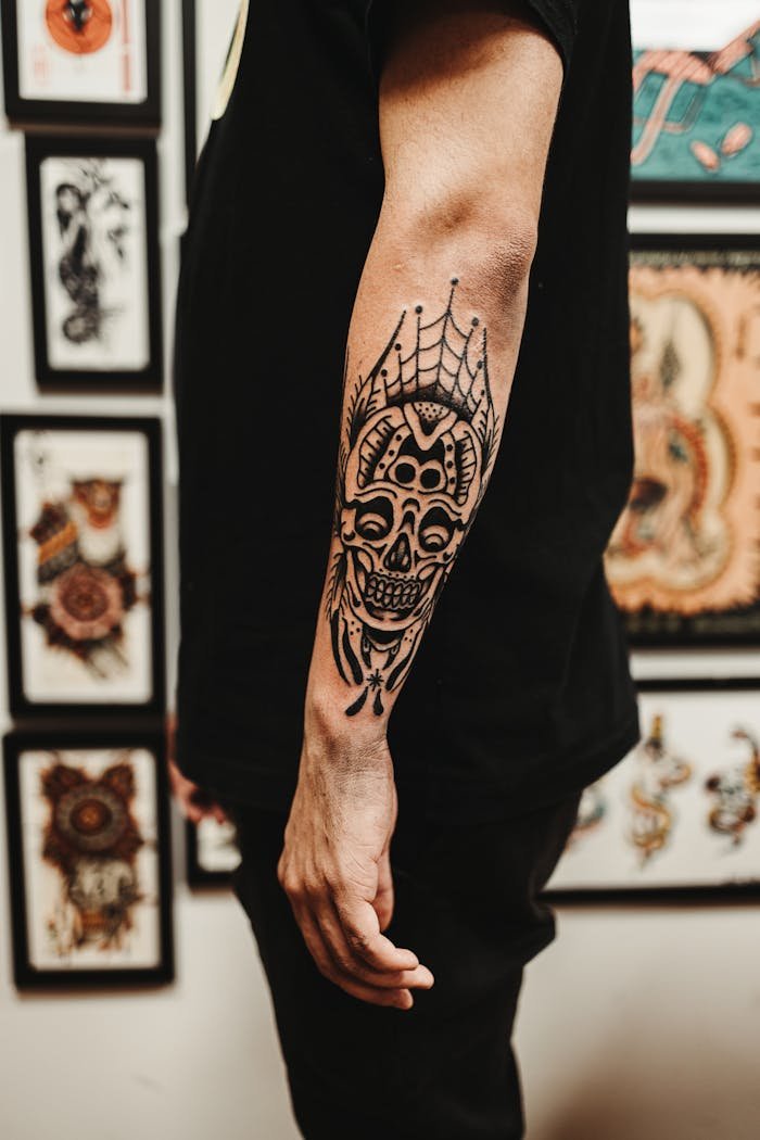 service-02 Detailed close-up of a mans arm with an intricate skull tattoo in an artistic setting.