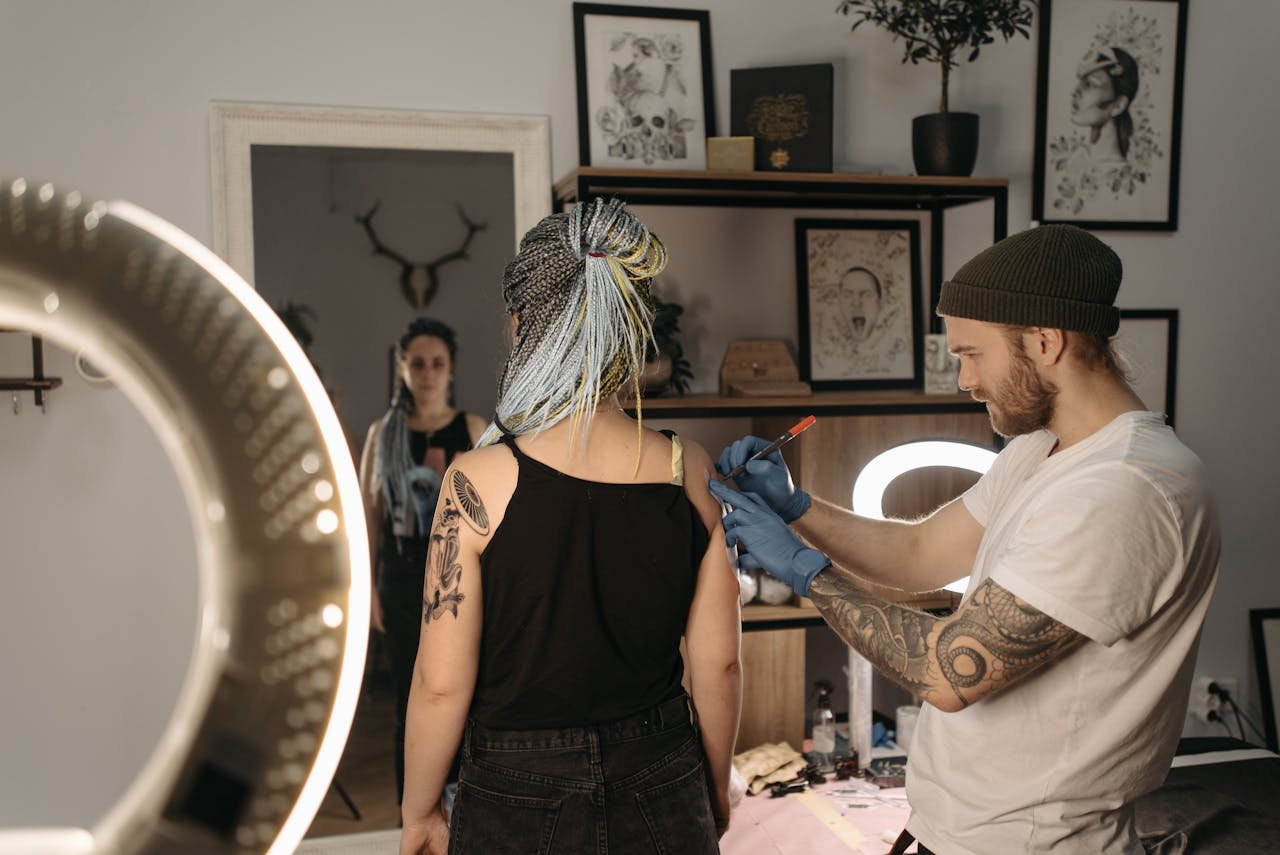 why-choose-me-02 Tattoo artist creating artwork on clients arm in a studio setting.